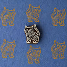 Hand-carved wooden stylized cat printing block with repeated ochre cat impressions on blue handmade paper, traditional Indian textile stamp.