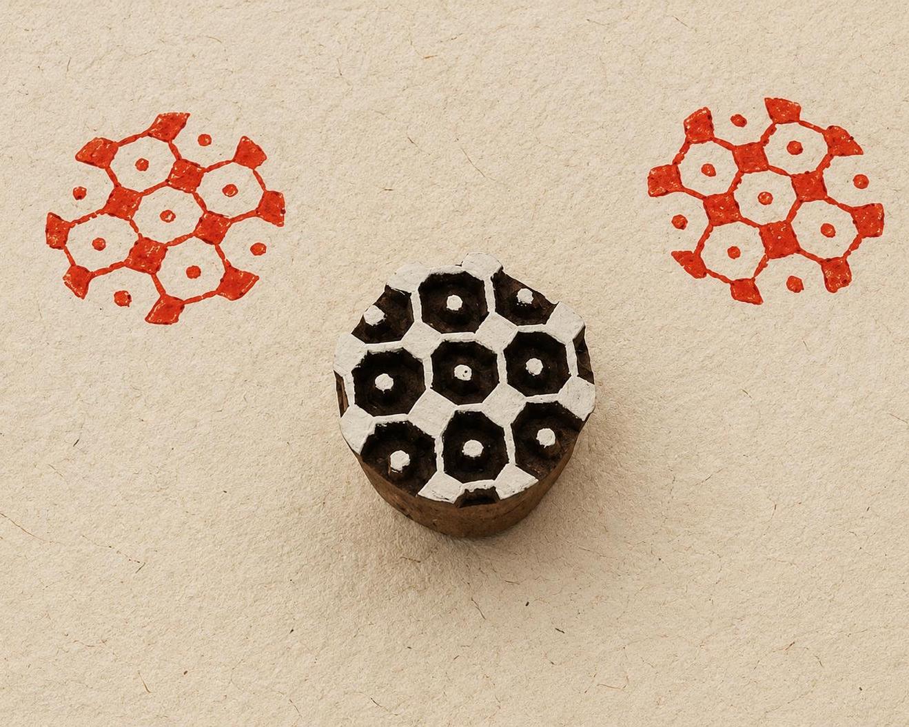 Hand carved wooden printing block featuring a honeycomb pattern with red stamped impressions on handmade paper.