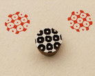 Hand carved wooden printing block featuring a honeycomb pattern with red stamped impressions on handmade paper.