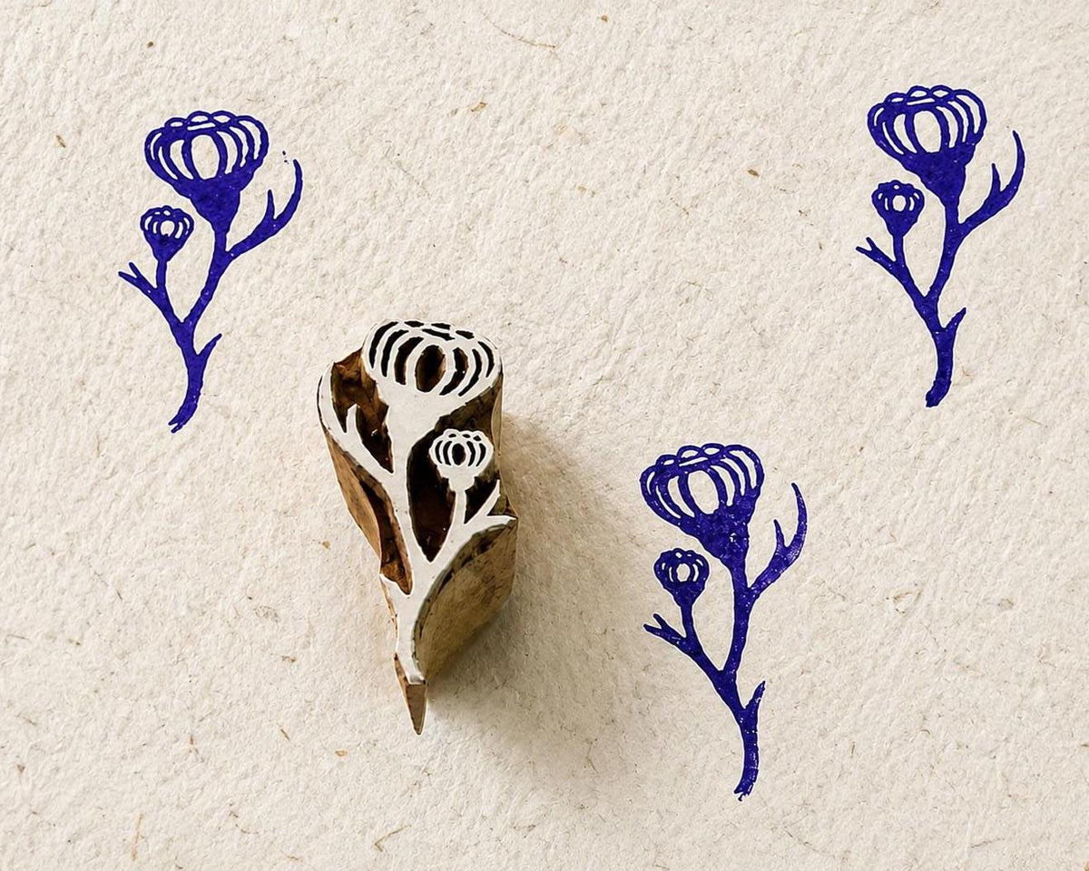 Hand carved wooden printing block featuring a bluebell sprig with purple stamped impressions on handmade paper.