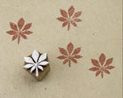 Hand carved wooden printing block featuring a seven petal bloom motif with terracotta stamped impressions on handmade paper.