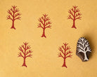 Hand-carved wooden leafless tree branch printing block with repeated red branch impressions on handmade paper, traditional Indian textile printing stamp.