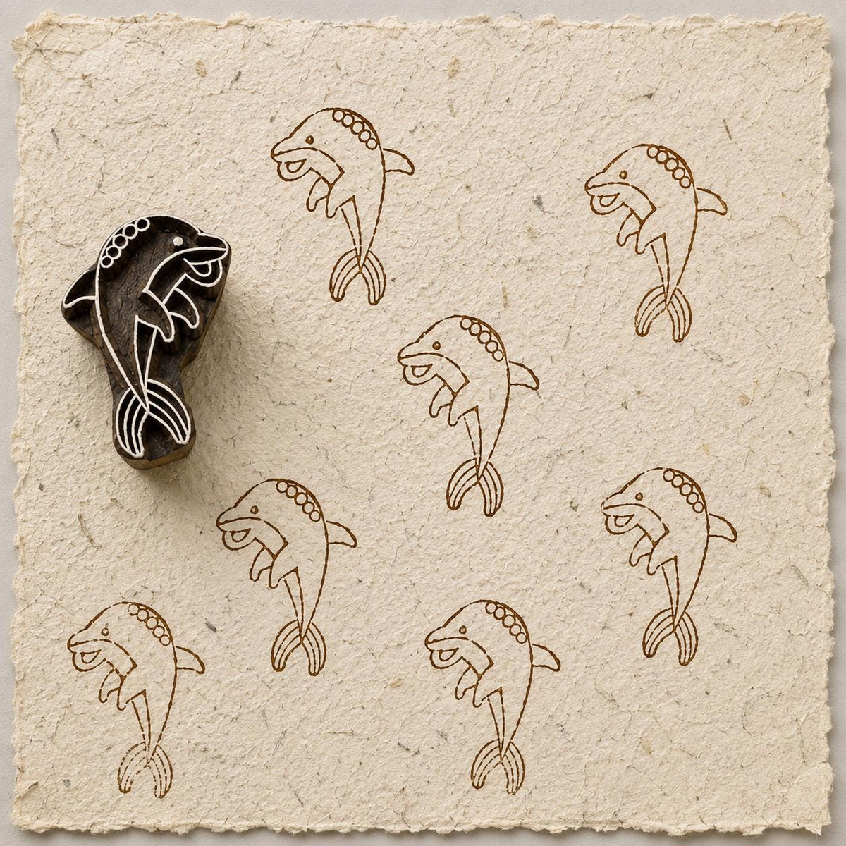 Hand carved Playful Dolphin wooden printing block with stylized dolphin print on handmade paper.