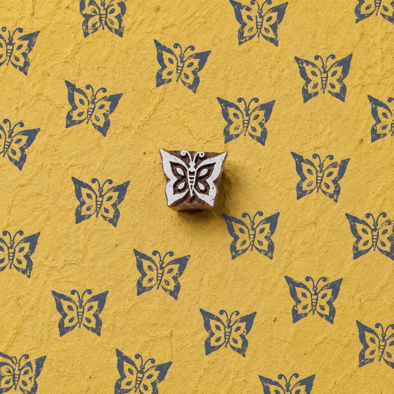 Hand carved Flutter Butterfly wooden printing block with decorative butterfly print on handmade yellow paper.