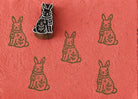 Hand-carved wooden winter bunny printing block with sweater and snowflake design, stamped repeatedly on coral handmade paper for Christmas fabric and paper crafts.