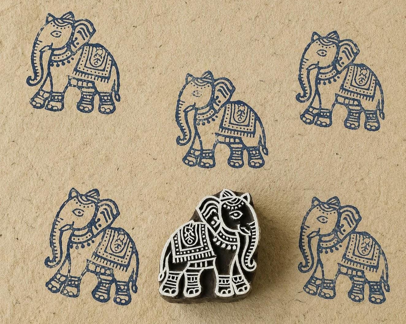 Hand-carved wooden Indian elephant printing block with repeated navy blue elephant impressions on handmade paper, traditional textile stamp.