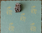 Hand-carved wooden woodland deer printing block with repeated pale yellow deer impressions on blue handmade paper.