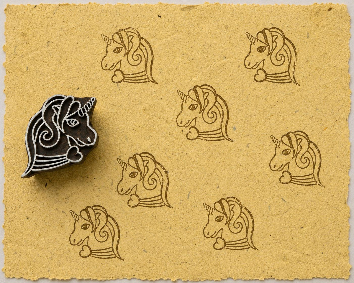 Hand-carved unicorn wooden printing block with repeated brown unicorn impressions on textured mustard yellow handmade paper.