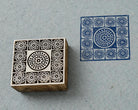 Hand carved wooden printing block featuring a royal courtyard medallion design with a blue stamped impression on handmade paper.