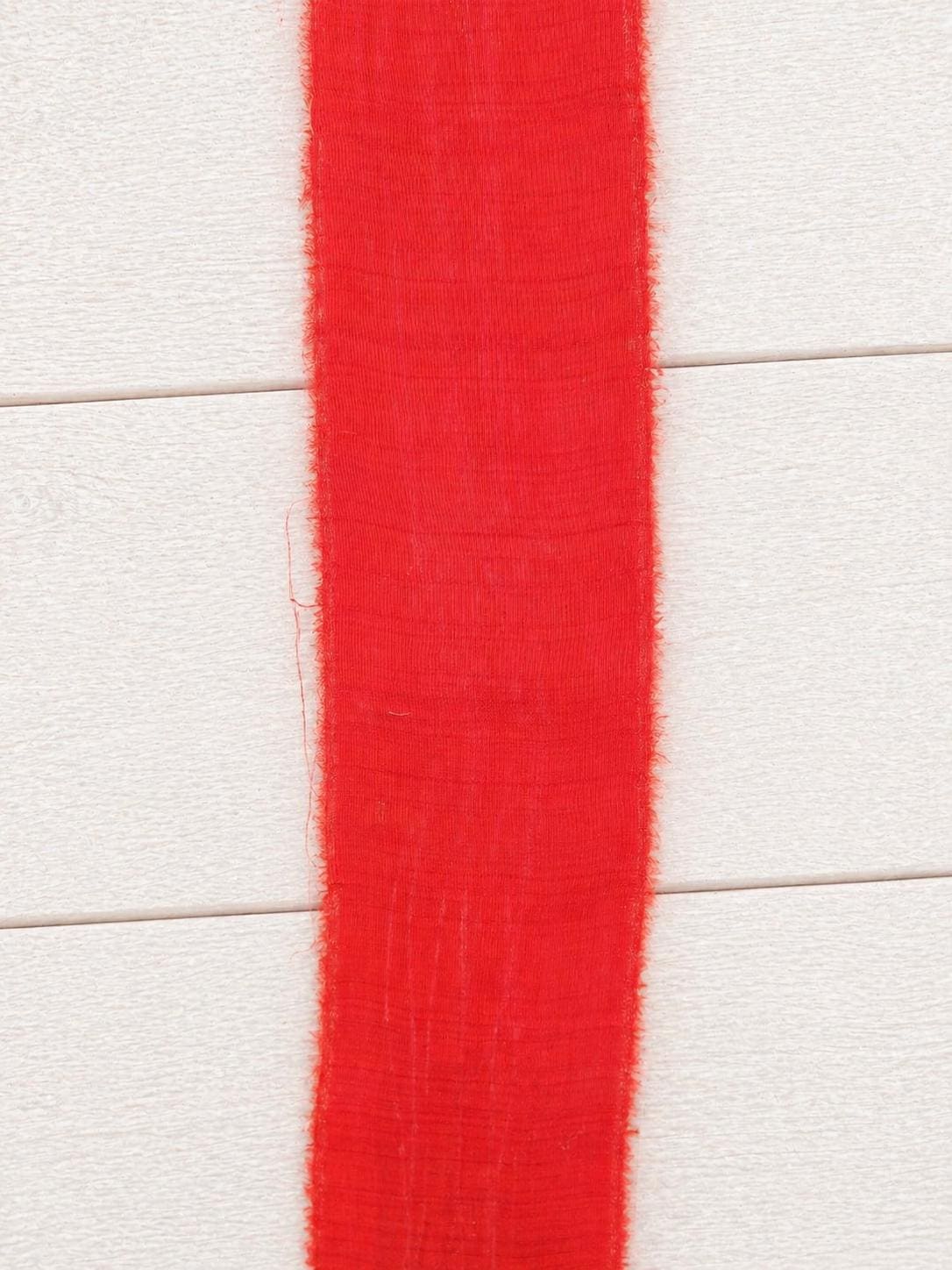 Flat section of wide vermilion sari silk ribbon displaying the smooth silk weave and generous width.