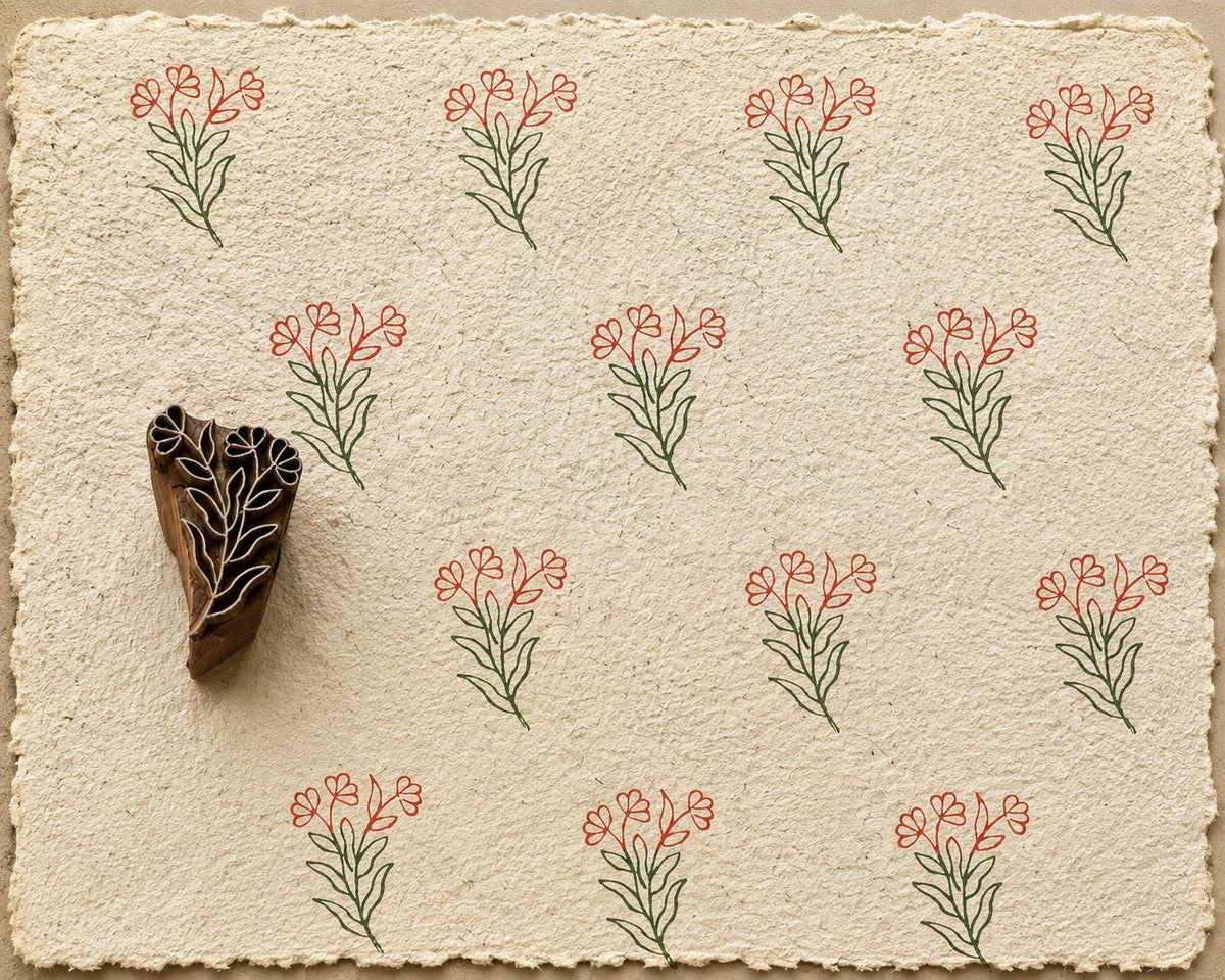 Hand carved Heart Bloom wooden printing block with delicate heart-shaped floral stem printed on handmade paper in earthy red and green ink.