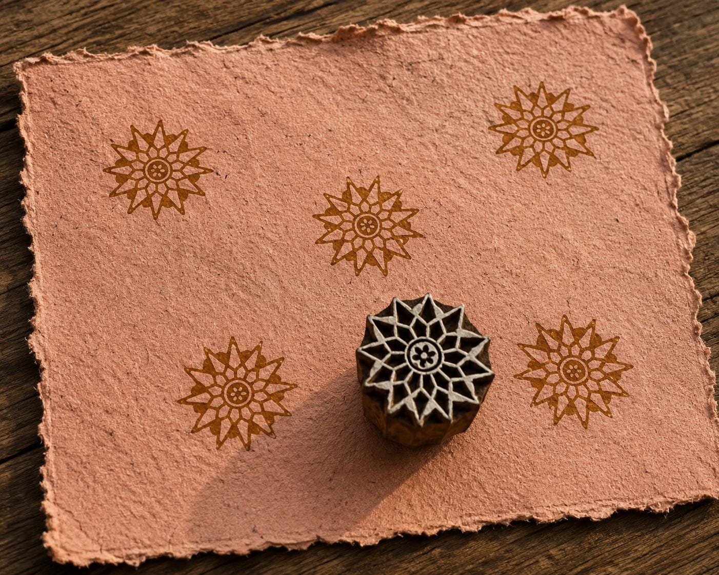 Hand-carved Sunburst Bloom wooden printing block with floral impressions on blush handmade paper.