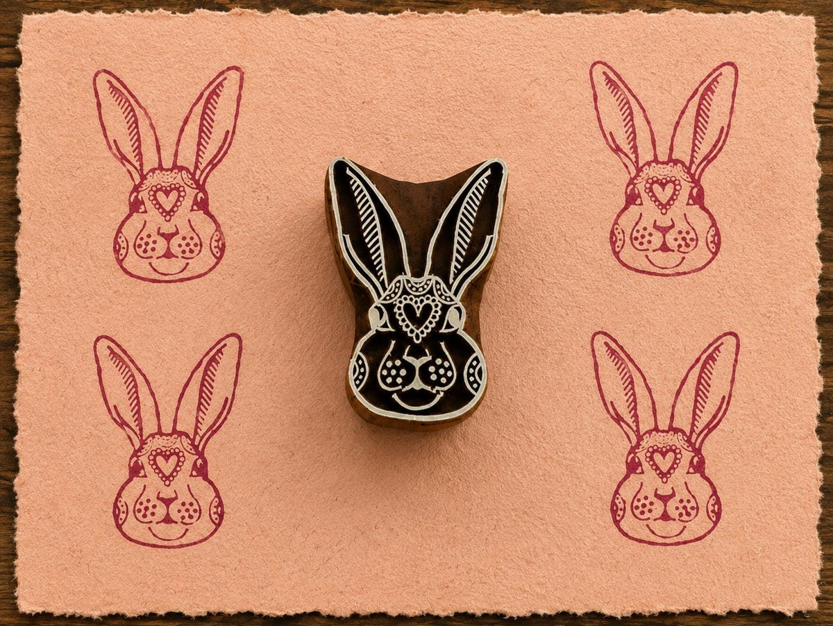 Hand-carved Heart Bunny wooden printing block with magenta rabbit impressions on blush handmade paper.