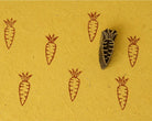 Hand-carved wooden carrot printing block with repeated carrot impressions on mustard handmade paper. Perfect for fabric printing, paper crafts, journaling, and DIY projects.
