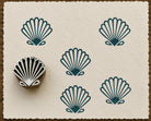 Hand-carved Scallop Shell wood block stamp with teal shell impressions on textured handmade cream paper.