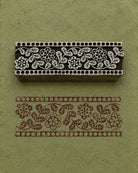 Hand-carved floral border wooden printing block with botanical border impressions on sage green handmade paper for fabric printing and paper crafts.