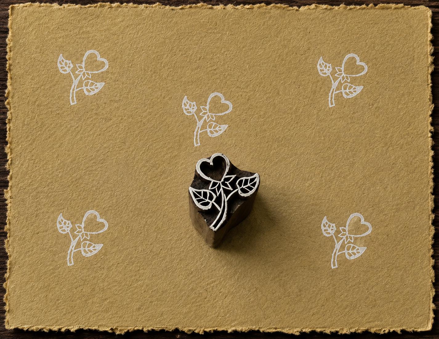 Hand-carved Heart Blossom wood block stamp with white heart flower impressions on mustard handmade paper.
