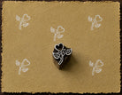 Hand-carved Heart Blossom wood block stamp with white heart flower impressions on mustard handmade paper.