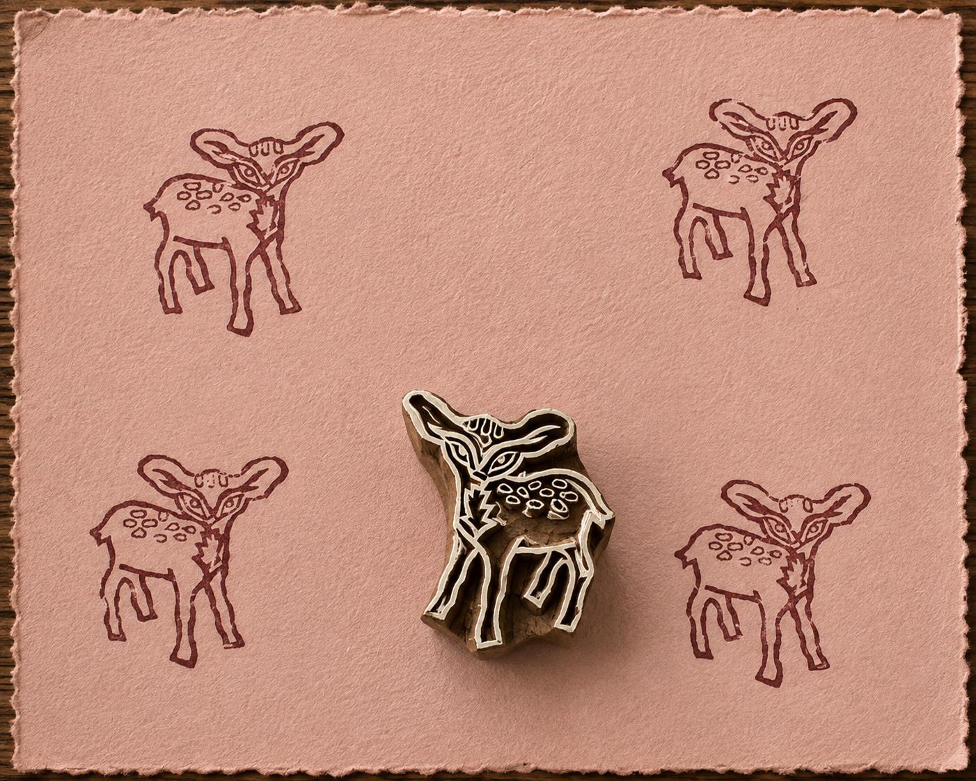 Hand-carved Woodland Fawn wood block stamp with brown deer impressions on blush handmade paper.