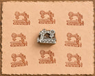 Hand-carved vintage sewing machine wooden printing block surrounded by repeated terracotta sewing machine impressions on peach handmade paper.
