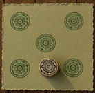 Hand carved Temple Circle wood block stamp with intricate circular pattern printed in green on handmade paper for fabric printing, pottery, clay and paper crafts.