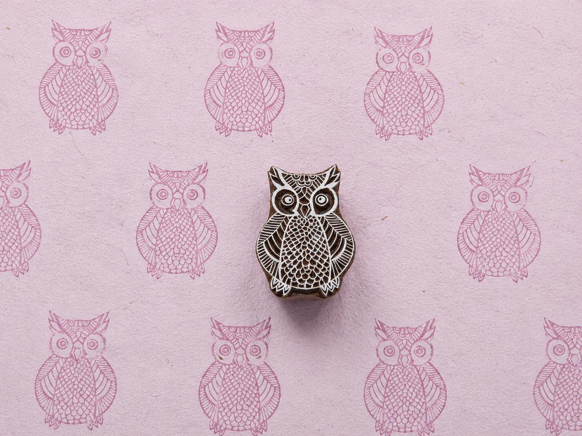 Hand-carved Hoot Owl wooden printing block with detailed owl impressions on textured pink handmade paper.