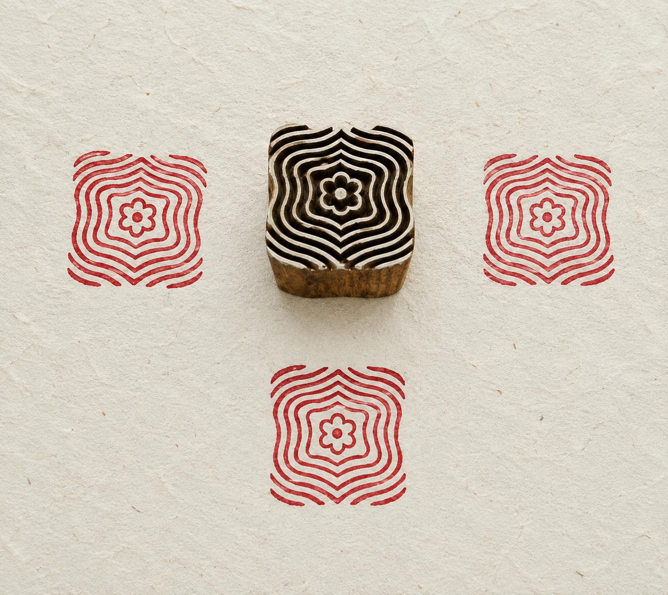 Hand carved Indian wooden textile printing block featuring a Ripple Bloom geometric motif with concentric wavy lines and a floral center, stamped in red on handmade paper.