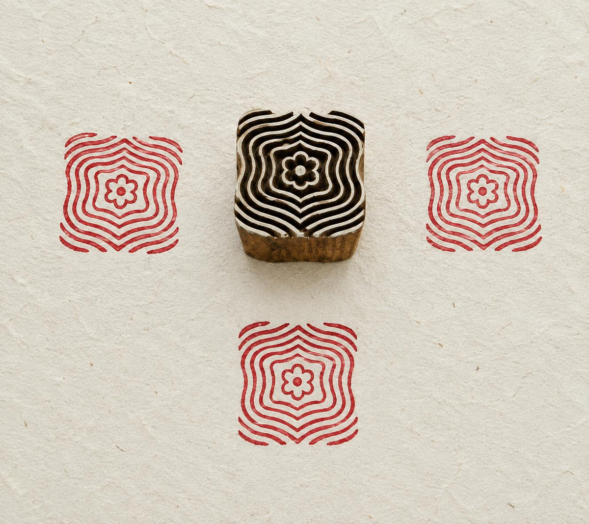 Hand carved Indian wooden textile printing block featuring a Ripple Bloom geometric motif with concentric wavy lines and a floral center, stamped in red on handmade paper.