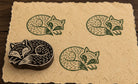 Hand-carved Sleeping Fox wooden printing block with green fox impressions on natural handmade paper.
