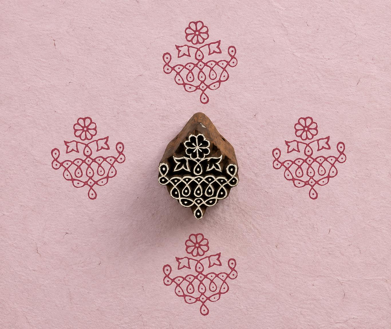 Hand carved Indian textile printing block with an ornate Temple Garland motif, shown with four red impressions on handmade pink paper.