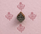 Hand carved Indian textile printing block with an ornate Temple Garland motif, shown with four red impressions on handmade pink paper.