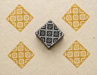 Hand carved wooden stamp printing yellow diamond geometric pattern on fabric