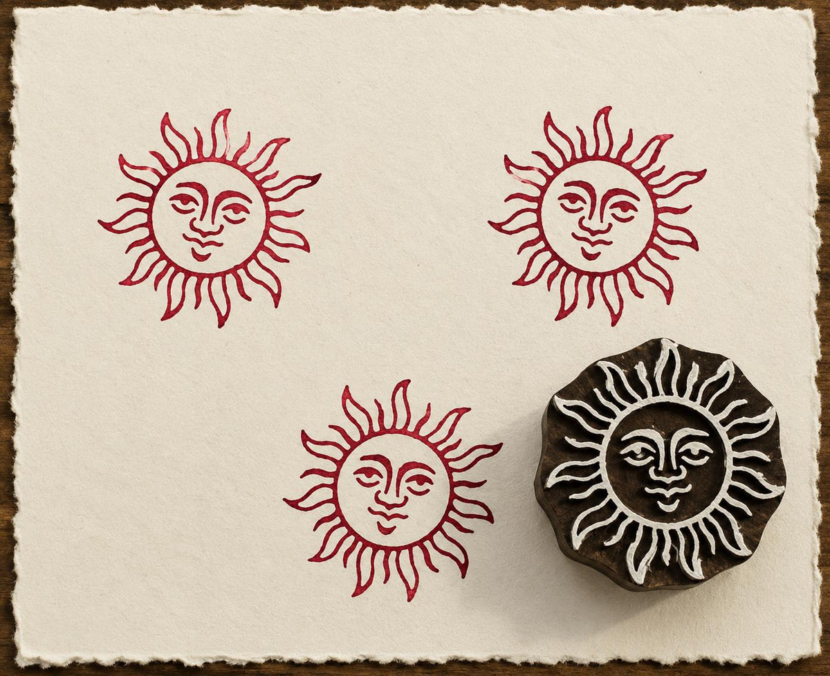 Hand-carved Smiling Sun wooden printing block with deep red celestial sun impressions on textured handmade paper.