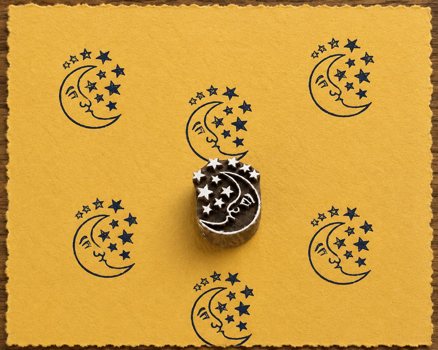 Hand-carved Starlit Moon wooden printing block with navy blue moon and stars impressions on mustard handmade paper.