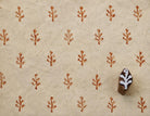 Hand-carved 2 cm wooden printing block with a small branch motif, shown beside repeated reddish-brown impressions on handmade cream paper.
