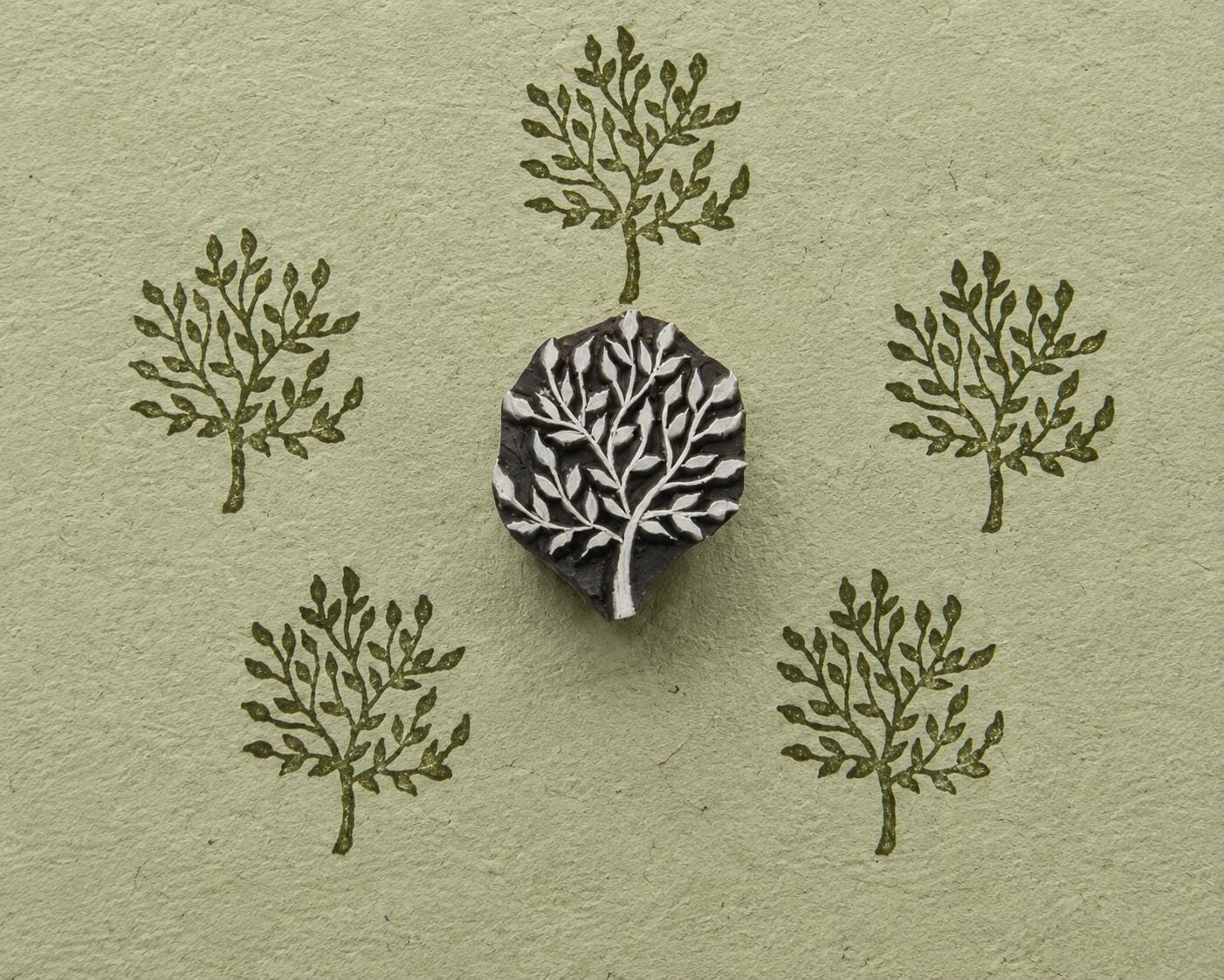 Hand carved wooden Meadow Tree stamp shown with repeated leafy tree impressions on textured handmade paper.