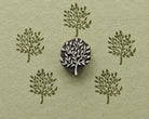 Hand carved wooden Meadow Tree stamp shown with repeated leafy tree impressions on textured handmade paper.
