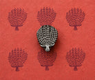 Hand carved wooden Lace Tree stamp shown with repeated dark purple tree impressions on textured red handmade paper.