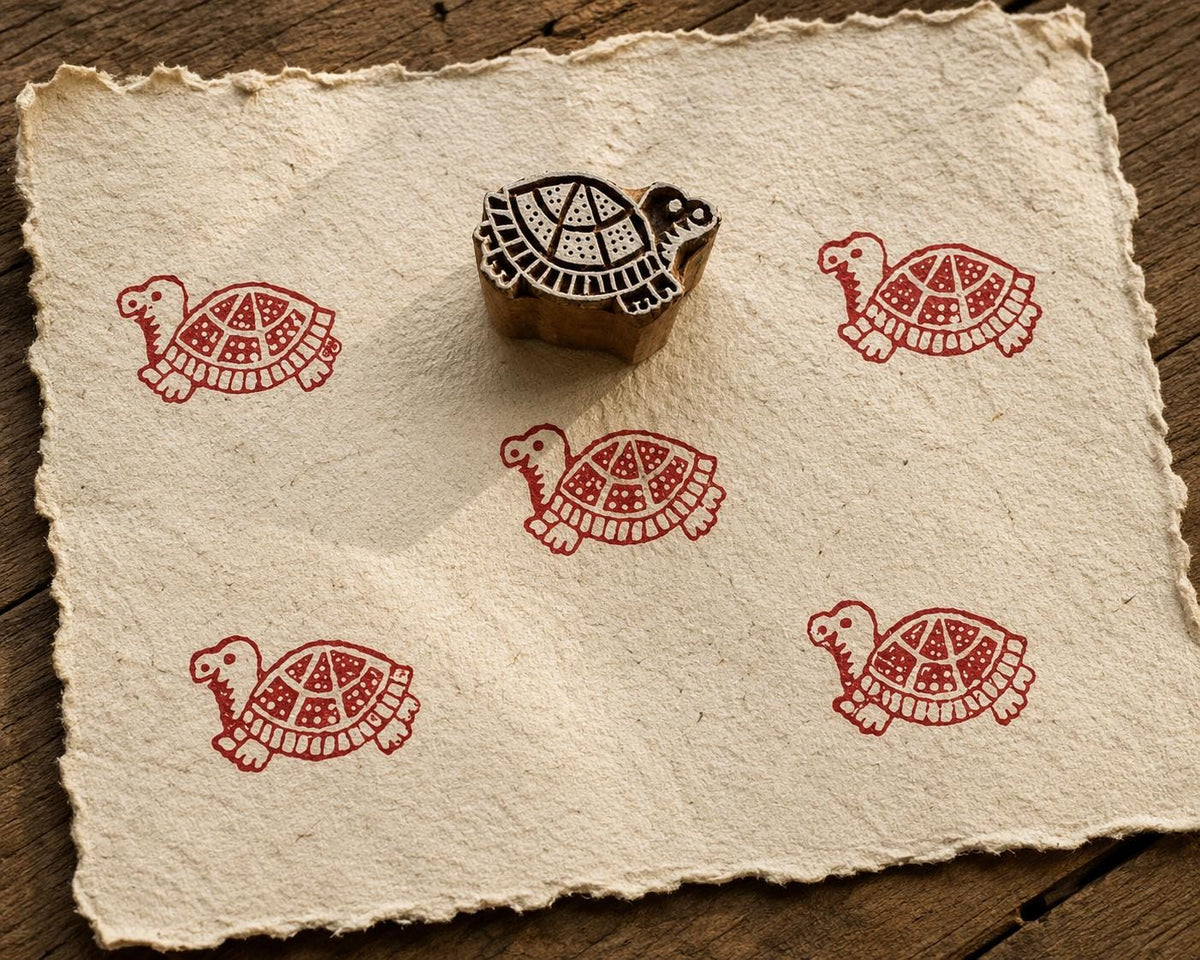 Hand carved turtle wood block stamp with red turtle print on handmade paper, ideal for fabric printing, pottery, clay, paper and textile crafts.