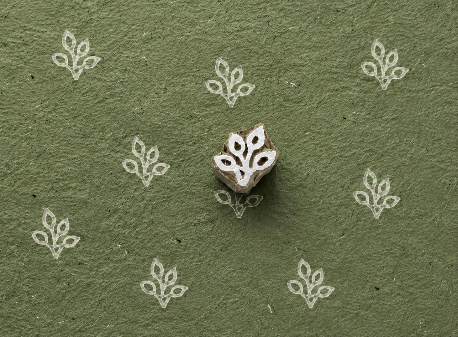 Four Loop Leaf wooden stamp shown with repeated white impressions on textured green handmade paper.