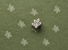 Four Loop Leaf wooden stamp shown with repeated white impressions on textured green handmade paper.