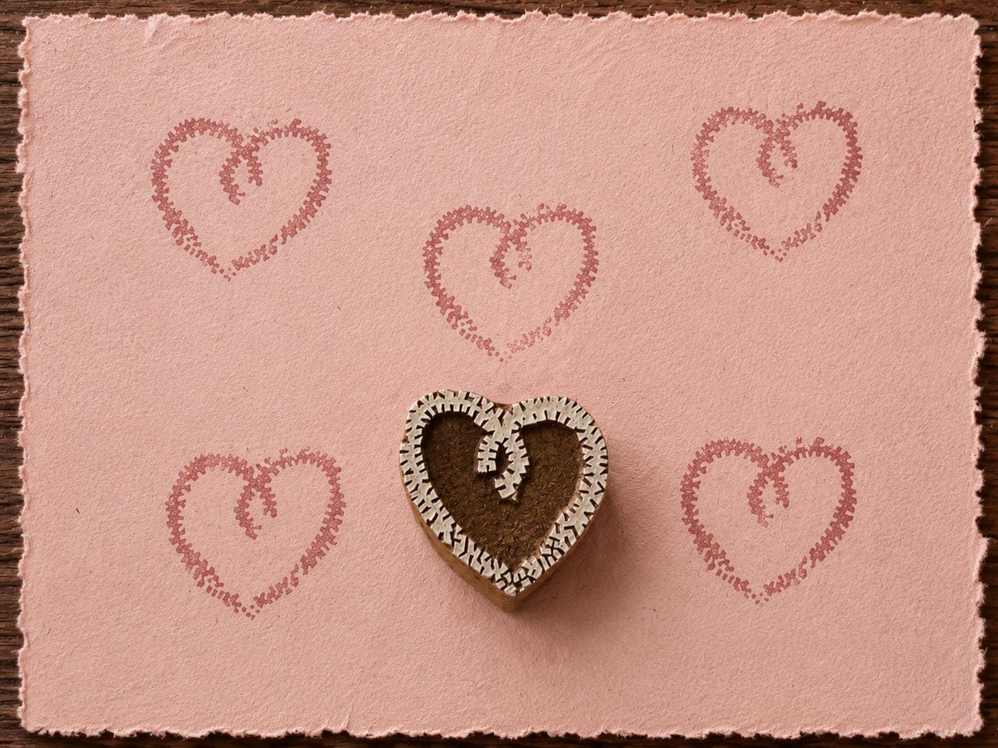 Hand carved Stitched Heart wood block stamp with a decorative stitched heart print on pink handmade paper for fabric printing, pottery, clay and paper crafts.