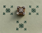 Hand carved Indian wooden printing block featuring a tribal cross geometric pattern with dark green impressions on handmade paper.