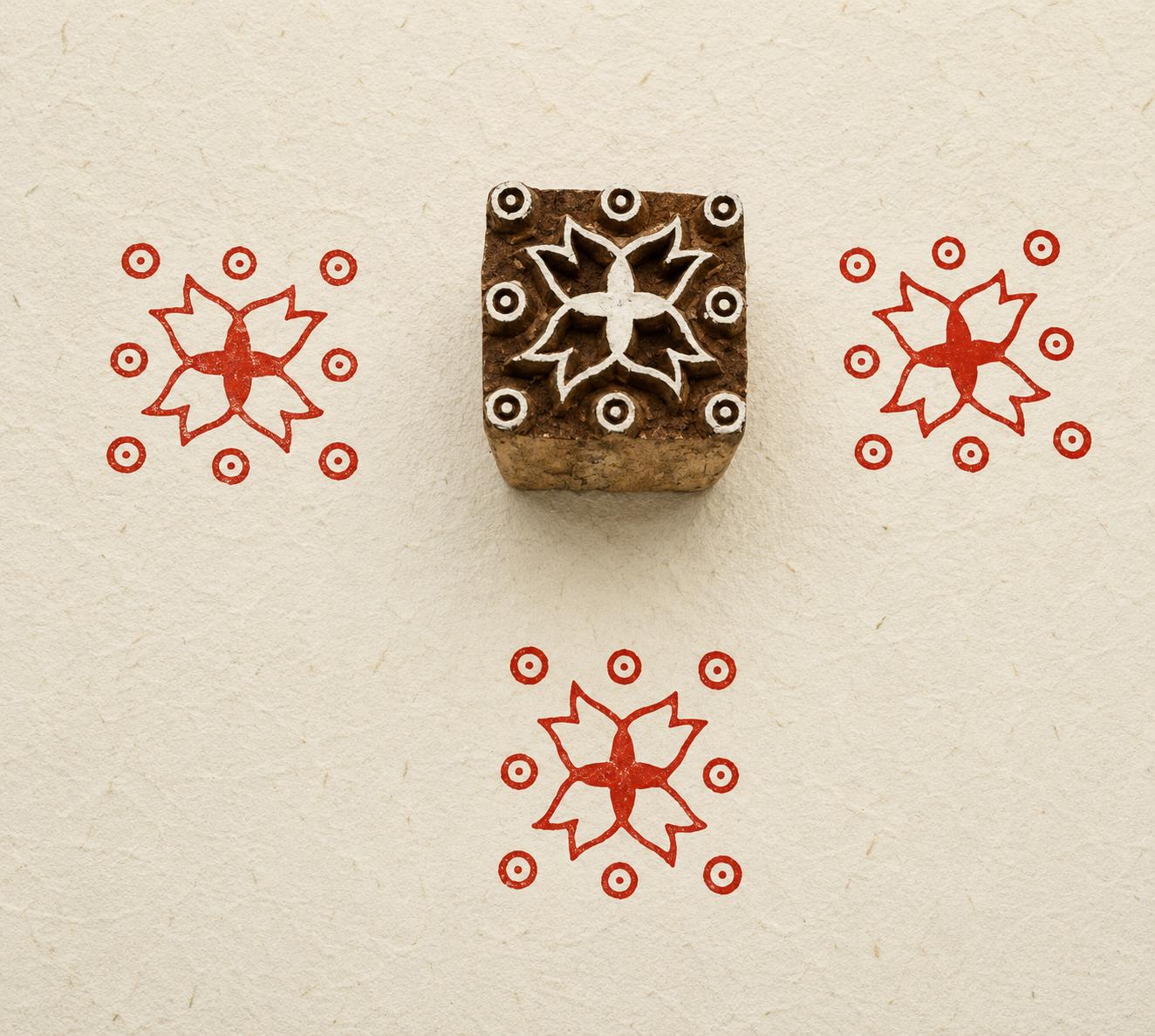 Hand carved Indian wooden textile printing block featuring a Temple Star floral motif with circular accents, stamped in red on handmade paper.