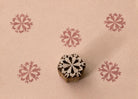 Hand-carved wooden printing block featuring a symmetrical folk starburst motif, shown with five dusty rose impressions on textured handmade paper.