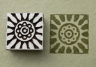 Hand carved Sunburst Flower wood stamp beside its green floral impression on textured handmade paper.