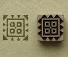 Hand carved geometric square wood block stamp with olive green impression on handmade pale green paper