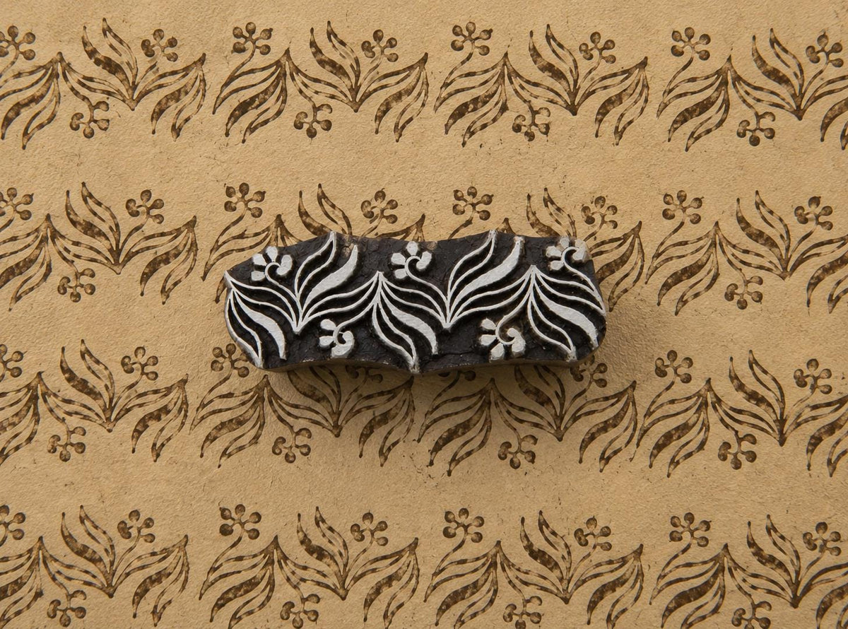 Hand carved foliage border wooden printing block shown on handmade paper with a repeating brown botanical border pattern.