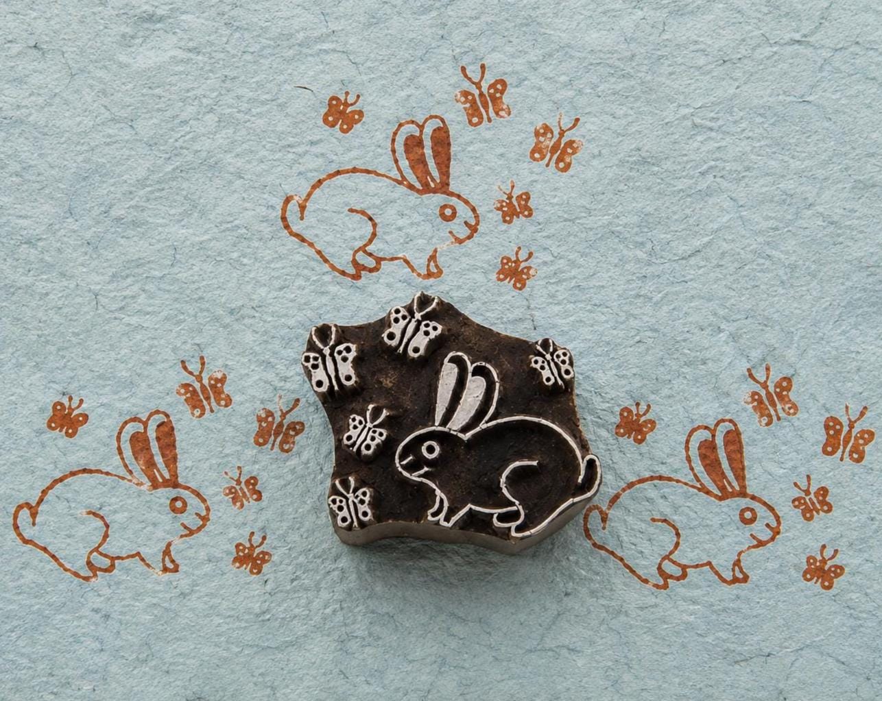 Hand-carved rabbit woodblock with butterfly motifs printed on handmade blue paper