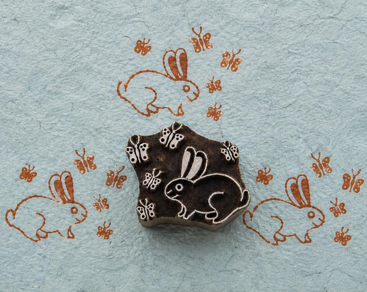 Hand-carved rabbit woodblock with butterfly motifs printed on handmade blue paper